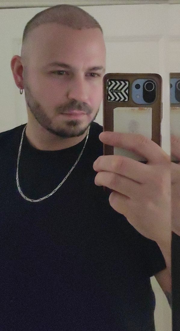 Man in a mirror around six months after a hair transplant, hair cut very short