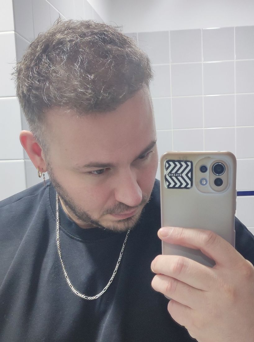 Man photographed in a bathroom mirror with a full head of styled hair